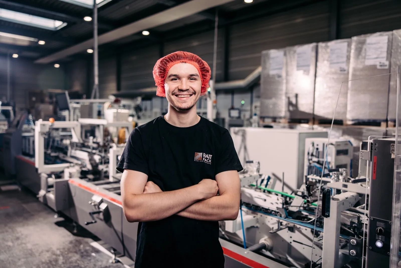 Lehrling mit Haarnetz an einer Maschine in der Produktion